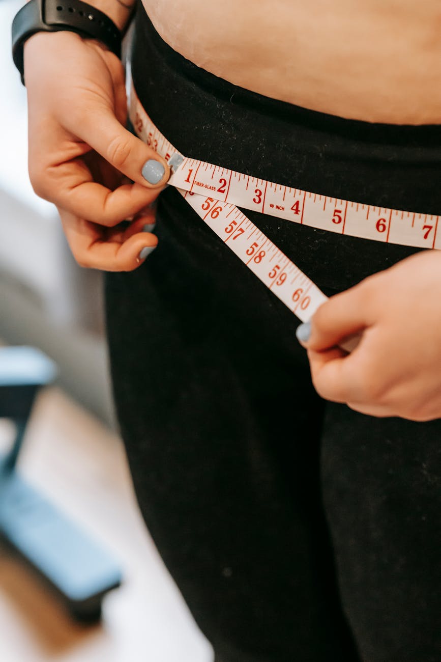 plus size woman measuring hips in gym